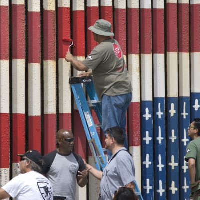 USA:s flagga målas upp och ned på en bit av muren mellan USA och Mexiko