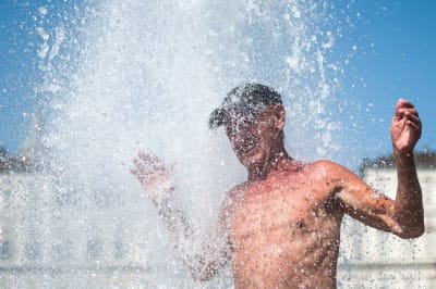 En man njuter av vattnet i värmen på Piazza Castello i Turin, Italien 12.8.2021