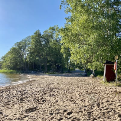 Sandstrand med röda badhytter. Sol, sommar.