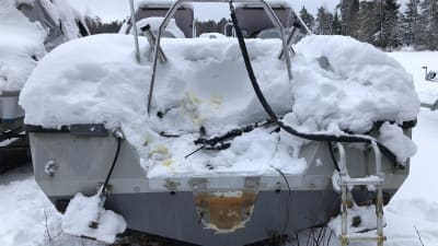 En båt täckt av snö där utombordsmotorn har tagits bort.