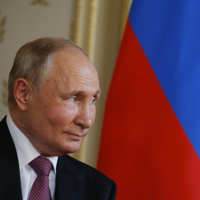 Vladimin Putin i profil framför den ryska flaggan under ett möte med Schweizs president Guy Parmelin (inte på bild).