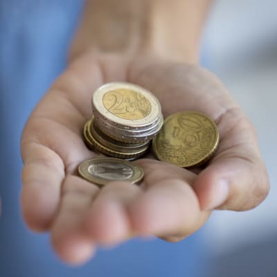Två öppna händer med några slantar i var hand. 