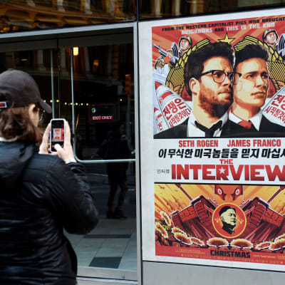Kvinna fotograferar reklamaffisch för The Interview utanför Regal Theater i New York den 18 december 2014.