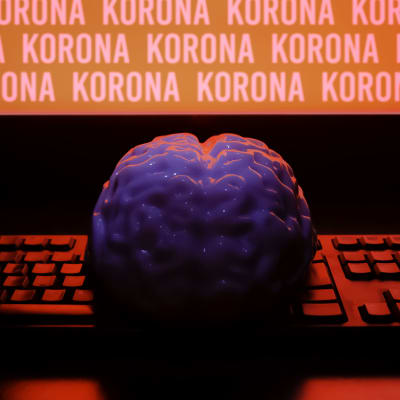 Aivot tietokoneruudun edessä, ruudulla toistuu sana korona.