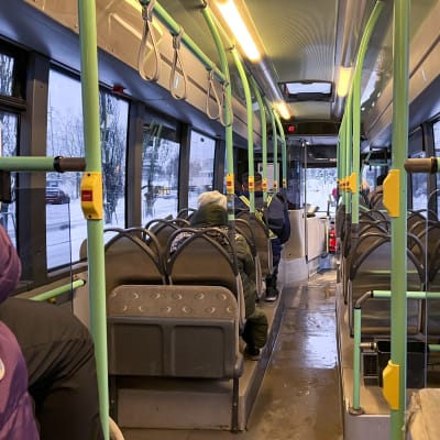 Ihmisiä matkustamassa paikallisbussilla.