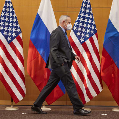 Personen går framför USA:s och Rysslands flaggor.