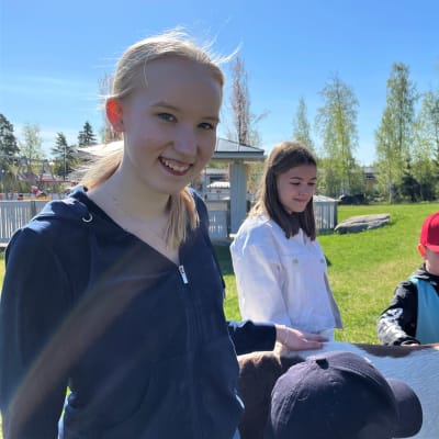 Borgaregatans skolanin kahdeksasluokkalainen Nea Hudd hymyilee kameralle päiväkodin pihassa. 