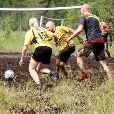 Kaksi naista ja kaksi miestä pelaavat jalkapallo suolla.