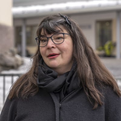 Pia Tyyskä står framför ett metallstaket.
