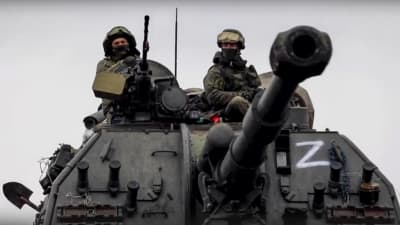 Två soldater sitter synligt på en rysk stridsvagn. På stridsvagnen har någon målat bokstaven Z i vit färg.