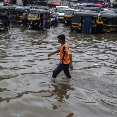 En man går genom översvämmade gator i utkanten av Bombay. 