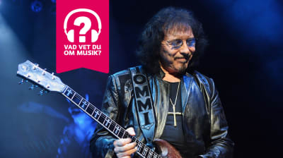Tony Iommi blundar, ler och spelar elgitarr.