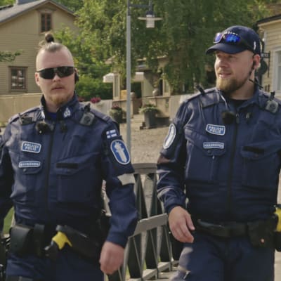 Kaksi poliisia, toisella aurinkolasit ja toisella lippis.