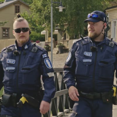 Kaksi poliisia, toisella aurinkolasit ja toisella lippis.
