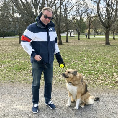 En man står med sin hund i en park. 