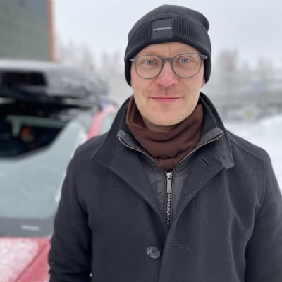 Hans-Alexander Öst står utomhus vid en bil. Han har på sig en mössa och vinterkläder.