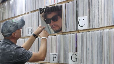 En man tar fram en Bob Dylan-skiva från en hylla med massor av lp-skivor.