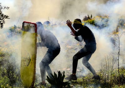 Palestinska ungdomar gömmer sig bakom en provisorisk sköld under konfrontationer med israeliska säkerhetsstyrkor, efter en demonstration mot Israels expropriering av mark i byn Kfar Qaddum nära den judiska bosättningen Kedumim på den ockuperade Västbanken, den 21 januari 2022.