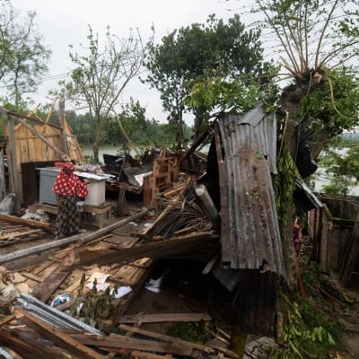 En person står mitt bland ett hus som totalförstörts i ett oväder.