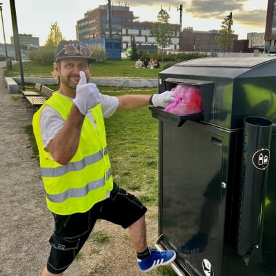 Mies laittaa roskapussin älyllä toimivaan roska-astiaan.