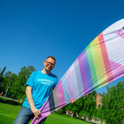 Sinuiksi ry:n toiminnanjohtaja Mikko Ala-Kapee seisoo nurmikentällä kädessään värikäs Sinuiksi ry:n roll up.