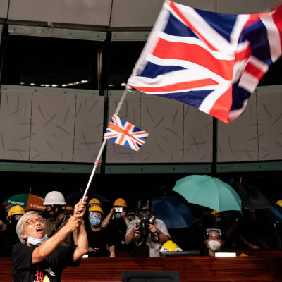 En demonstrant viftar med den brittiska flaggan efter att demonstranter stormat lokalstyrets byggnad i Hongkong.