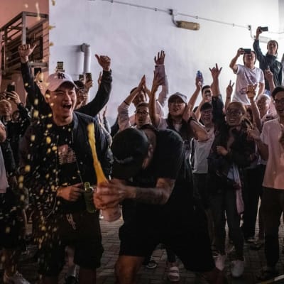 Firande oppositionsanhängare öppnar en champagneflaska utanför en vallokal i Hongkong