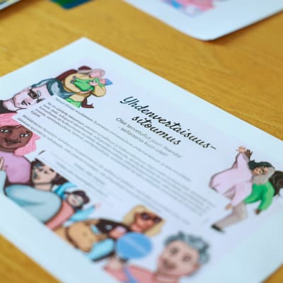 Valkoinen paperi pöydällä. Paperissa on piirrettyjä hamoja ja tekstiä, otsikkona "Yhtenvertaisuussitoumus".