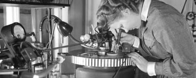 Lotta-pukuinen nainen työssä pikalevyjen äänityslaitteen äärellä 1940-luvulla. Ääniä ja radio-ohjelmia tallennettiin sellakkakalvopintaisille metallilevyille.