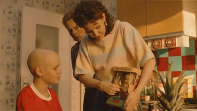 Tre av rollfigurerna från filmen står i köket. Johannes mamma visar en ny docka han ska få. 