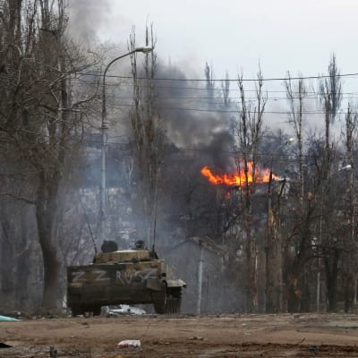 Venäjän tankki tiellä Mariupolissa, tulipalo taustalla, tiellä paljon romua.