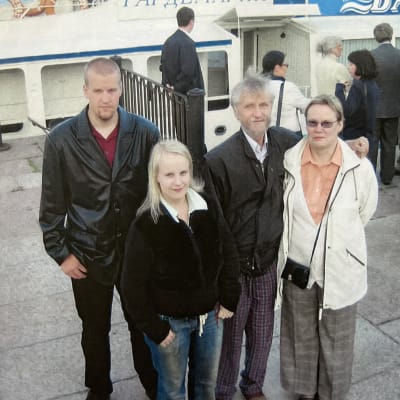 Kauko Purasen perhe Pietarissa jokiristeilylaivan edustalla, seisovat vierekkäin ja katsovat kameraan.
