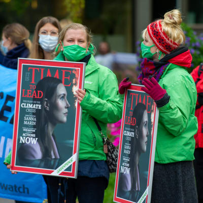 Demonstranter utanför Ständerhuset bär plakat med bild på statsminister Sanna Marin på omslaget till tidskriften Time. 