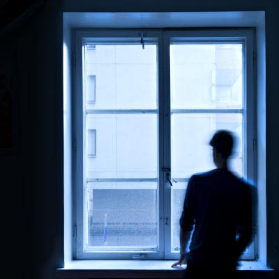 Ihminen seisoo ikkunan ääressä