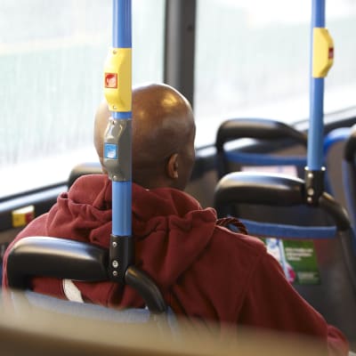 En flintskallig mörkhyad man sitter med ryggen till i lokalbussen.