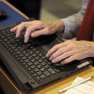 Äldre kvinna skriver på dator.