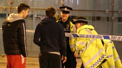Två poliser samtalar men två unga män i Manchester.