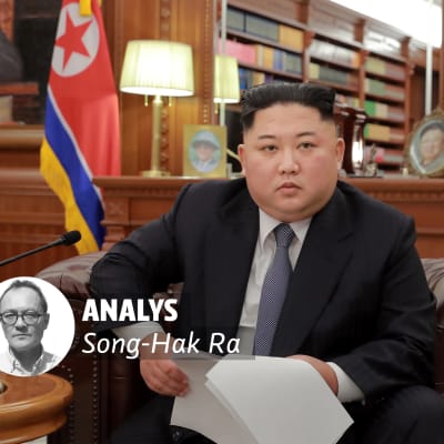 Kim Jong-Un sitter med en pappersbunt i handen.
