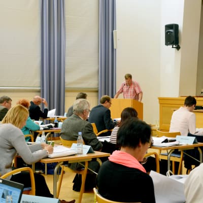 Ledamöter under ett fullmäktigemöte i Raseborg. SFP:s Björn Siggberg står i talarstolen.