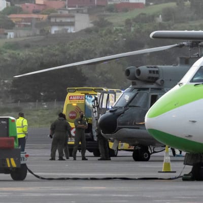 Ambulanssi, helikopteri ja lentokone lentokentällä.