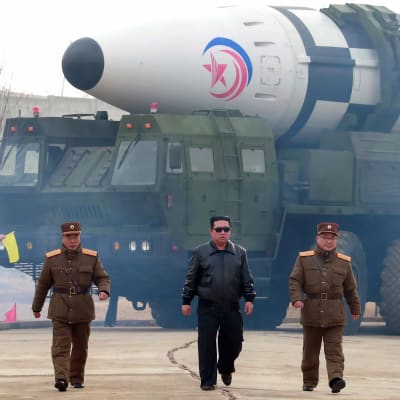 Kim Jong-un med solglasögon går iväg från en gigantisk robot.