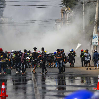 Polisen sprutar tårgas mo demonstranter i staden Mandalay. 