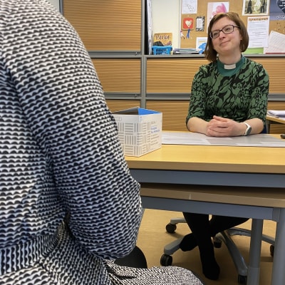 Diakoniatyöntekijä Kirsi Männistö istuu toimistossa asiakkaan kanssa.
