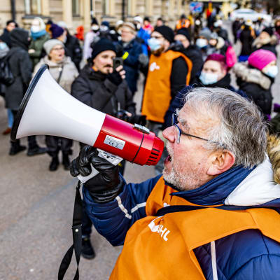 En man ropar i en megafon under en demonstration. 