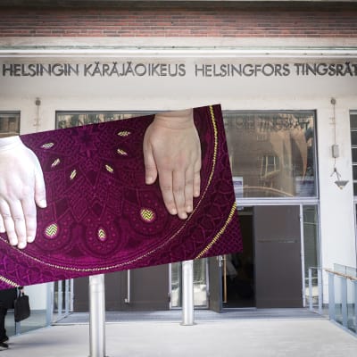Två händer på en matta inklippt framför Helsingfors tingsrätts byggnad.