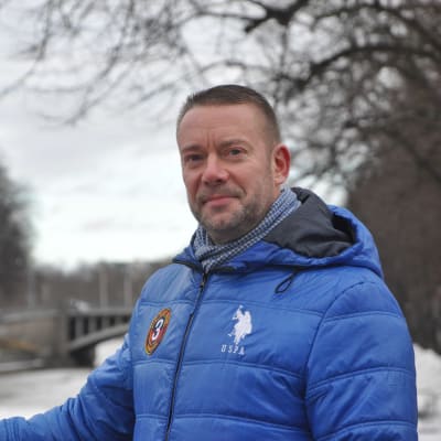 Stefan Wallin står på Biblioteksbron i Åbo och tittar in i kameran.