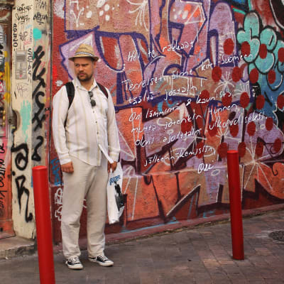 Olli Haapakangas seisoo graffitiseinän edessä.