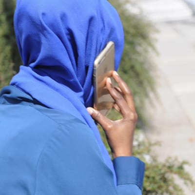 Muslimsk kvinna talar i mobiltelefon.