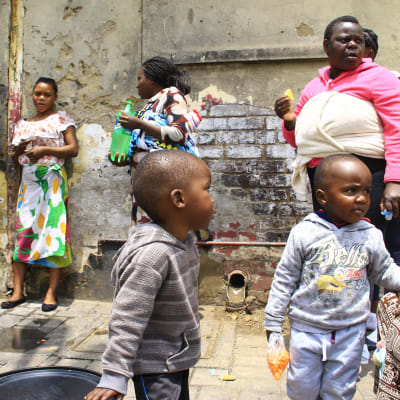 Kvinnor och barn står utanför ett övergivet hus i Zimbabwe.