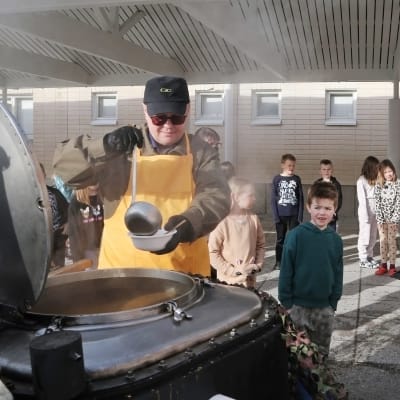 Yrittäjä Matti Henttunen jakaa koululaisille soppatykillä tehtyä keittoa Napapiirin ala-asteella Rovaniemellä.